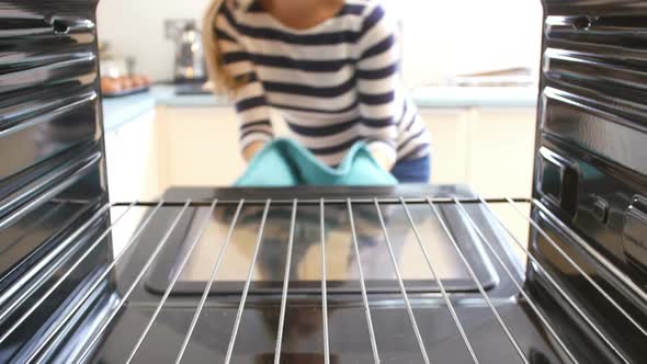 Woman Taking Cooked Stuffed Mushrooms Out Of The Oven