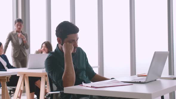 A young company employee is feeling tired while sitting at work for a long time.