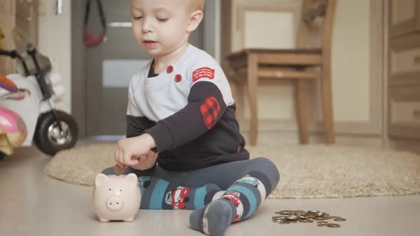 Little Boy Putting Coins Into Piggy Bank for the Future Savings at Home.