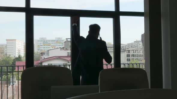 Silhouette of Businessman Talking on the Phone Near the Window