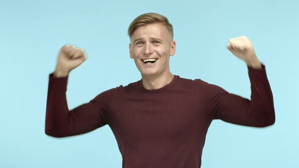 Young Blond Man Winning Prize and Celebrating Raising Hands Up and Saying Yes with Triumph Making