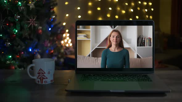 A Young Woman Waves Hello and Smiles on a Videocall 