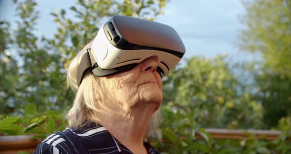 Grandma Turning Her Head in Virtual Reality Glasses and Looking at the Camera Smiling