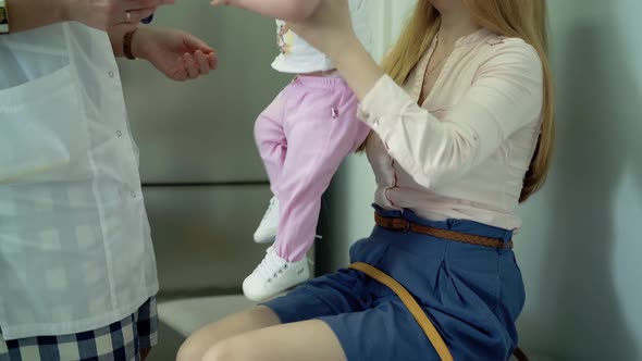 Young Mother Holds a Baby in Her Arms a Doctor Examines