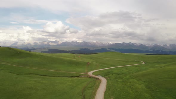 Mountain peaks and grassland under white clouds