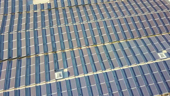 Aerial view of many photo voltaic solar panels mounted of industrial building roof.