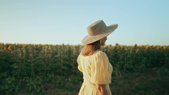 Unrecognizable Woman in Retro Dress Walking Alone Near Sunflowers Field