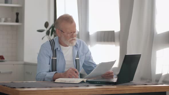 Modern Pensioner Accountant Freelancer Performs Routine Work at Laptop While Sorting Out Accounts at