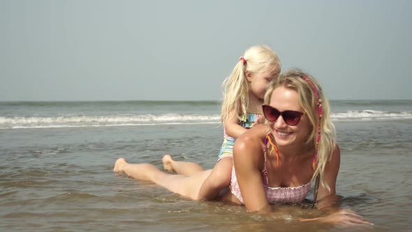 Happy Family, Mom and Child Sunbathe on the Sea Beach