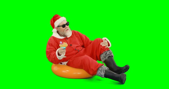 Santa claus sitting on inflatable tube and having cocktail