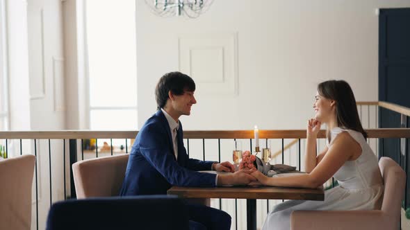 Handsome Guy Is Talking To His Girlfriend on Date Sitting at Table Together and Laughing Enjoying