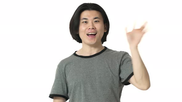 Portrait of Friendly Chinese Man with Clean Skin in Casual Gray Tshirt Grinning and Greeting with