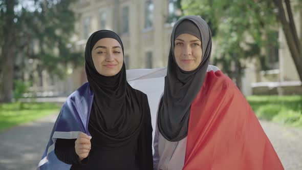 Middle Shot of Young Muslim Women Wrapped in French Flag Looking at Camera and Smiling. Portrait of