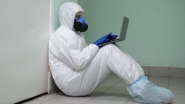 Tired Doctor in Protective Clothes Sitting on Floor Leaning