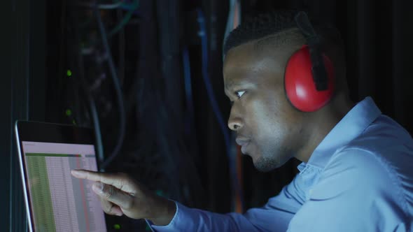 African american male computer technician using laptop working in business server room