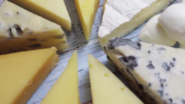 Different Varieties of Cheese for a Cheese Plate Lie on a Wooden Table