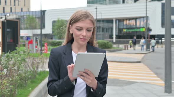 Attractive Young Businesswoman Using Tablet While Walking on the Street