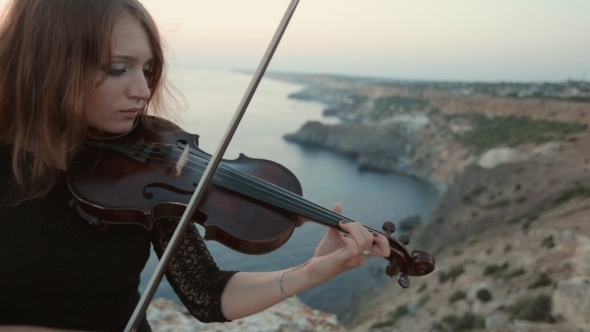 Violinist Stands On The Cliff On The Sea And Plays