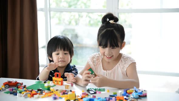 Little Asian Children  Playing With Colorful Construction Blocks On White Table