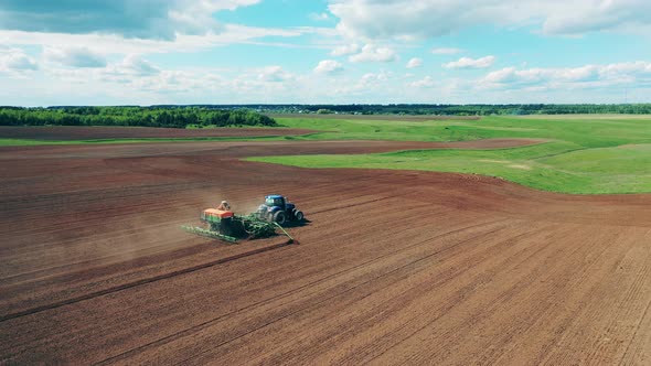 Blue Tractor Rides on a Field, Plowing Ground