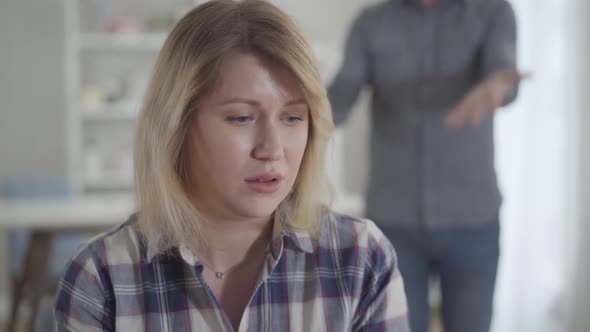 Close-up Face of Stressed Caucasian Young Woman Listening To Man Shouting at the Background