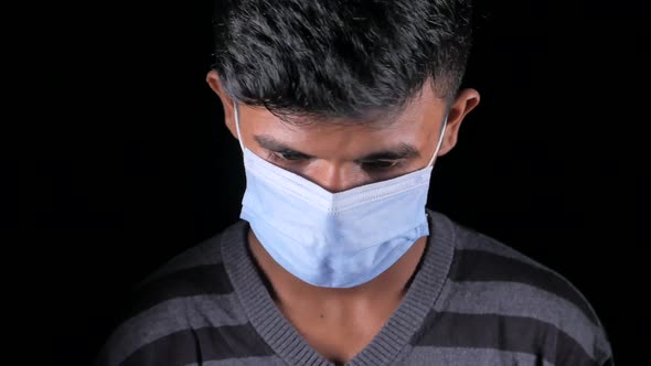 A Sad Young Man with Protective Mask Isolated on Black