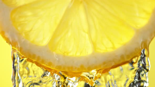 Super Slow Motion Macro Shot of Flowing Water From Lemon Slice on Yellow Background at 1000Fps