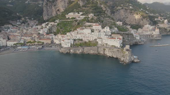 Aerial view of scenic Amalfi, Italy. Coastal town under rocky cliffs above Mediterranean sea, drone