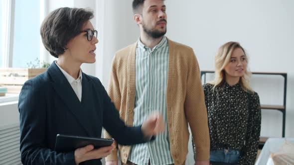 Housing Broker Showing Apartment To Couple of Customers Man and Woman Talking and Gesturing