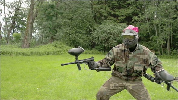 A Man in Pink Team Holding Two Paintball Guns