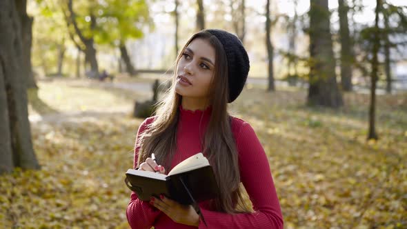 Young Poetess Inspects the Autumn Park and Writes Down Her Thoughts in Notebook