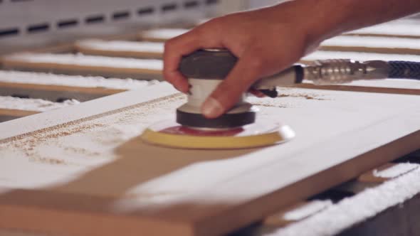 Slow motion of a worker polishing a cabinet door in a furniture factory