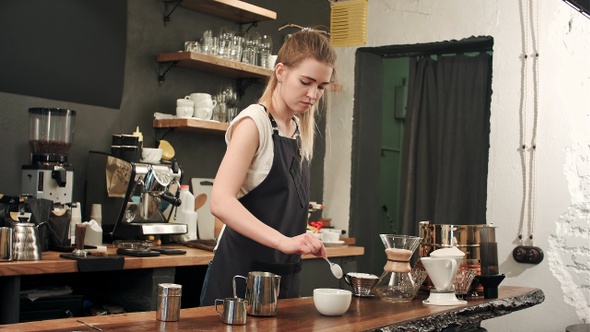 Pretty barista making coffee at cafe, pouring milk to a cup