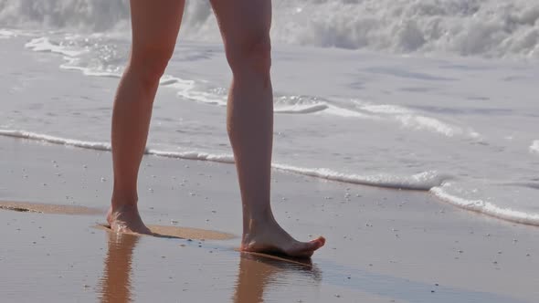 Woman Walking on Sand Beach. Closeup Detail of Foaming Waves of the Ocean