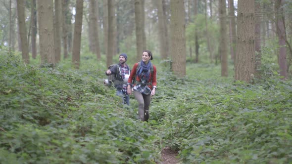 Couple carrying rucksacks and walking through dirt Tracking Left in forest