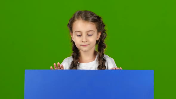 Child Looks Out From Behind a Blue Board and Shows a Thumbs Up. Green Screen