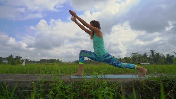 Slowmotion Steadicam Shot of a Young Woman Practicing Yoga on a Beautiful Rice Field