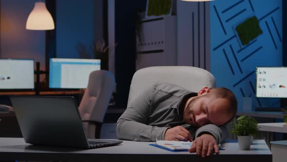 Exhausted Overworked Businessman Sleeping on Desk Table in Startup Business Office