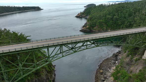Drone perspective of a single car driving across Deception Pass in Washington State.