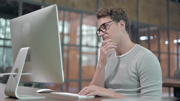 Ambitious Young Guy Thinking and Working on Computer