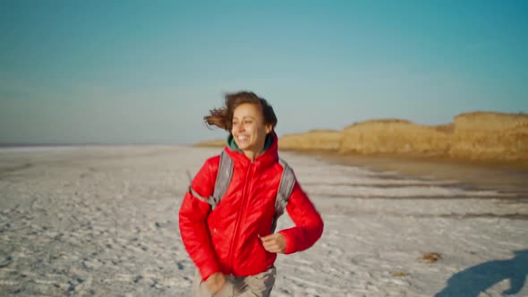 Slow Motion Free Happy Young Hiker Woman in Red Jacket Laughing and Running on Salt Desert Dry Coast