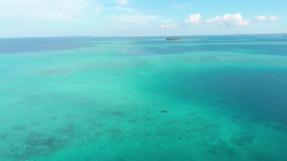 Aerial: flying over coral reef caribbean sea turquoise water, exotic tropical islands