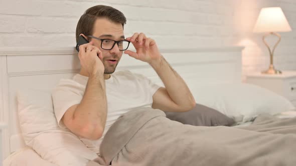 Young Man Talking on Smartphone in Bed