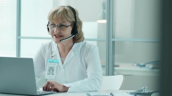 Senior Female Doctor Giving Online Consultation via Web Call in Clinic