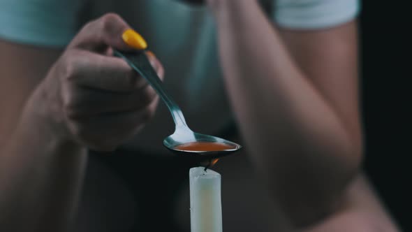 Woman Drug Addict Cooking Drugs in Spoon on Candle Flame