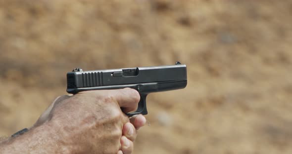 Slow motion of a hand gun firing in a firing range with cartridge flying away