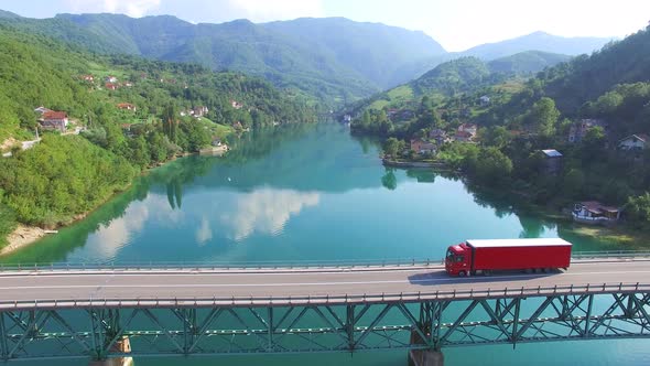 Big red truck driving on bridge over water