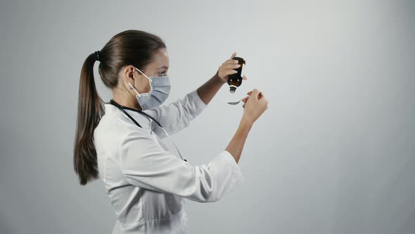 Female doctor dripping medicine from a bottle into a spoon