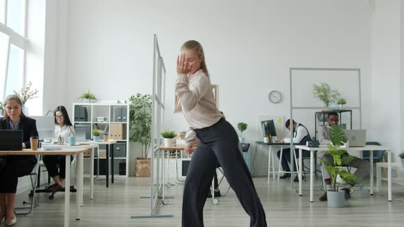 Beautiful Young Blonde Dancing in Office While Colleagues Clapping Hands in Background