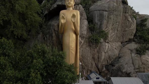 Ascending view of Golden Buddha Statue standing on Rock formation at seaside, Hua Hin